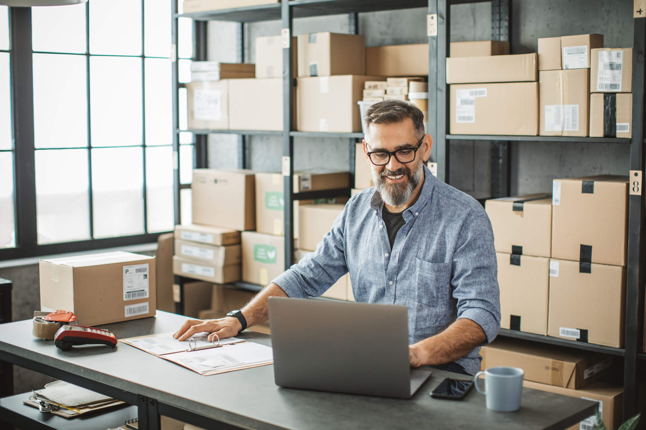 A focused worker seated at a laptop in a storage area, diligently addressing Extended Producer Responsibility (EPR) challenges.