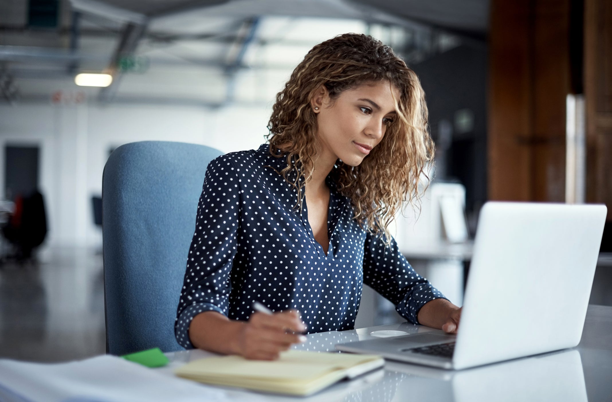 A professional woman sitting at a desk in an office setting, intently working on solving Extended Producer Responsibility (EPR) challenges.