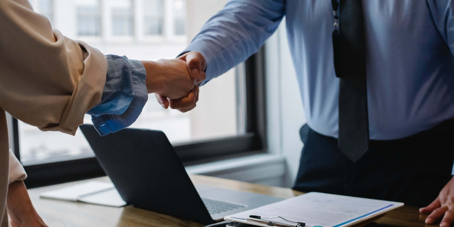 Two individuals engaging in a handshake, symbolizing agreement or partnership.